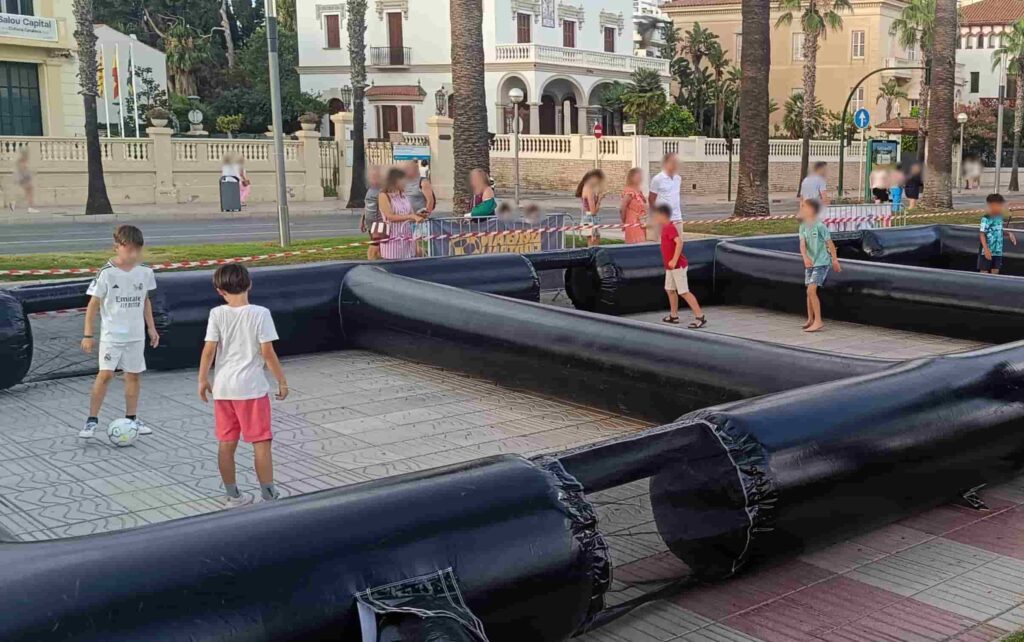 Niños jugando a fútbol panna en cancha hinchable 3x3 durante fiesta temática de fútbol